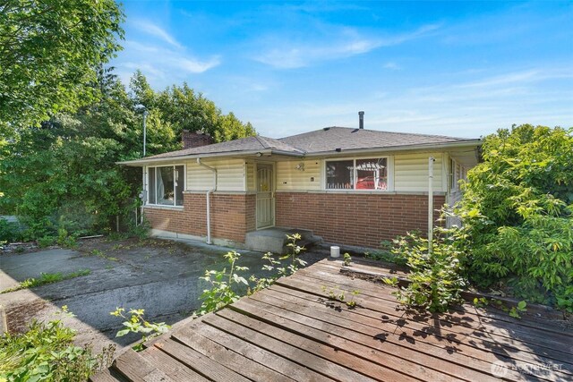 7919 37th Ave S, Seattle, WA 98118 - view of front of house with brick siding, a chimney, and a deck