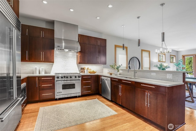 2334 N 57th St, Seattle, WA 98103 - kitchen featuring high end appliances, a sink, a peninsula, wall chimney range hood, and light countertops