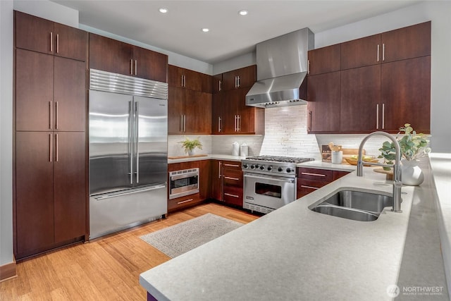 2334 N 57th St, Seattle, WA 98103 - kitchen featuring built in appliances, wall chimney exhaust hood, a sink, light wood-style flooring, and light countertops