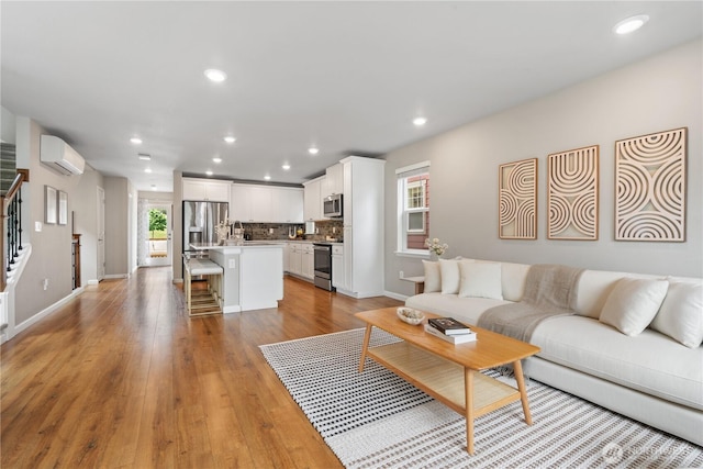 6730 34th Ave SW, Seattle, WA 98126 - living room featuring a wall mounted AC, recessed lighting, baseboards, light wood-type flooring, and stairs