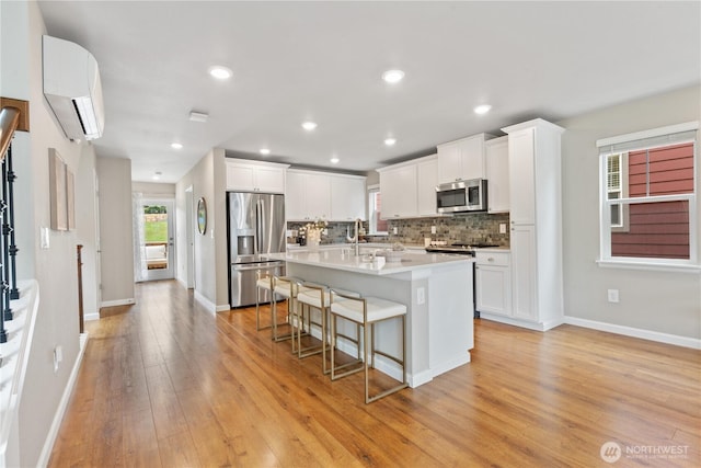 6730 34th Ave SW, Seattle, WA 98126 - kitchen with appliances with stainless steel finishes, a breakfast bar, an AC wall unit, light wood finished floors, and tasteful backsplash
