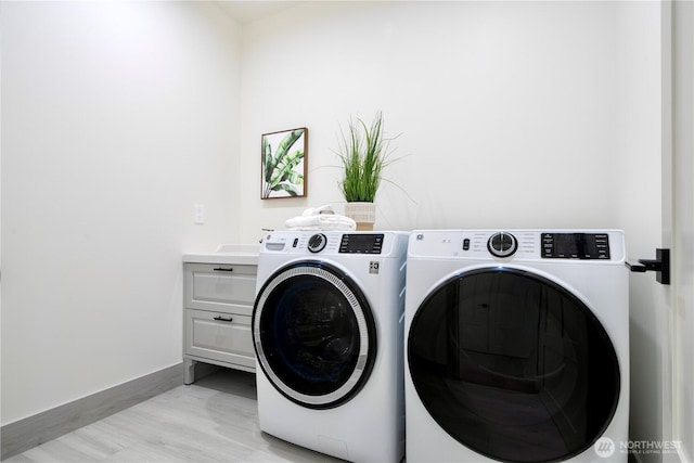 8456 SE 40th St, Mercer Island, WA 98040 - laundry area featuring separate washer and dryer, cabinet space, light wood-style floors, and baseboards