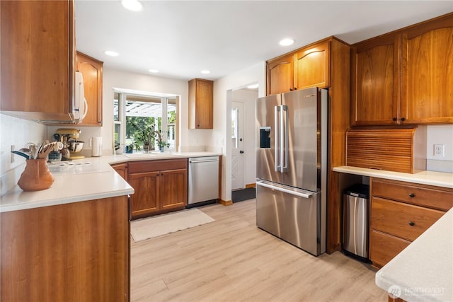 6888 Golf View Dr, Lynden, WA 98264 - kitchen featuring appliances with stainless steel finishes, a sink, light wood finished floors, brown cabinetry, and recessed lighting