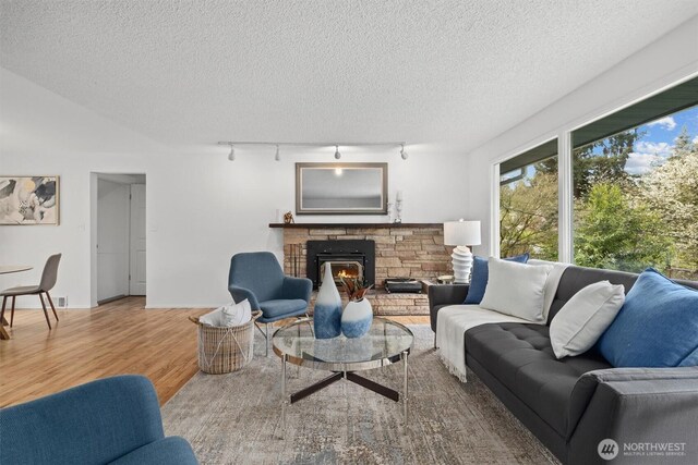 325 NE 178th St, Shoreline, WA 98155 - living room with rail lighting, wood finished floors, a textured ceiling, and a stone fireplace