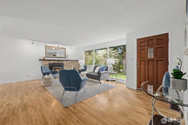 325 NE 178th St, Shoreline, WA 98155 - living room featuring a textured ceiling, light wood-style flooring, a glass covered fireplace, rail lighting, and baseboards