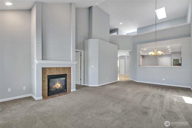 5909 Panorama Dr SE Unit 6-103, Auburn, WA 98092 - unfurnished living room with carpet floors, a tiled fireplace, a chandelier, a towering ceiling, and baseboards