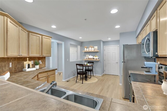 5909 Panorama Dr SE Unit 6-103, Auburn, WA 98092 - kitchen featuring appliances with stainless steel finishes, light wood-style floors, decorative backsplash, light brown cabinets, and a sink
