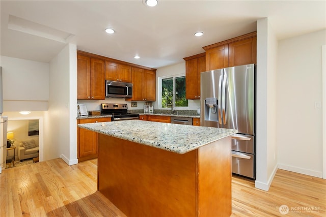 19802 33rd Dr SE, Bothell, WA 98012 - kitchen featuring appliances with stainless steel finishes, light wood-style floors, a kitchen island, light stone countertops, and brown cabinetry