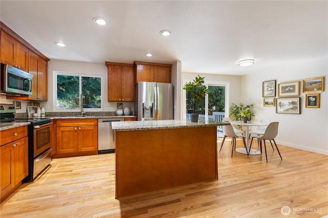 19802 33rd Dr SE, Bothell, WA 98012 - kitchen featuring appliances with stainless steel finishes, stone counters, light wood-style floors, brown cabinetry, and a kitchen island