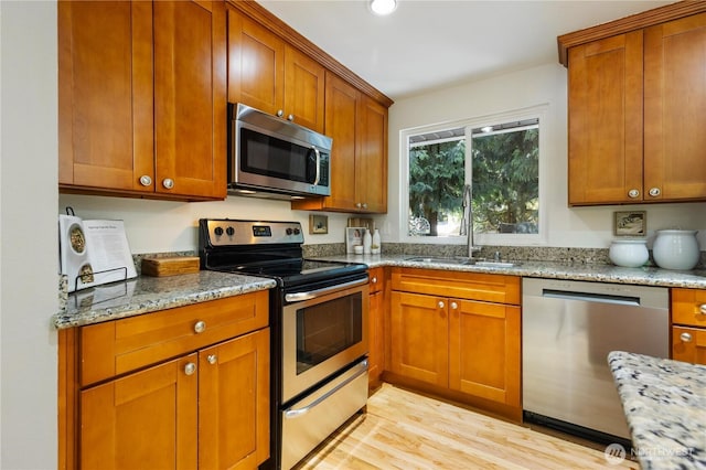 19802 33rd Dr SE, Bothell, WA 98012 - kitchen with appliances with stainless steel finishes, a sink, light stone countertops, light wood-type flooring, and brown cabinetry