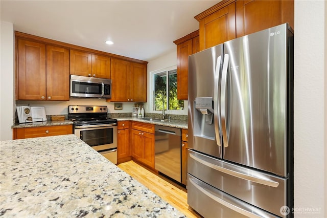 19802 33rd Dr SE, Bothell, WA 98012 - kitchen with stainless steel appliances, brown cabinets, light wood-style floors, light stone countertops, and recessed lighting