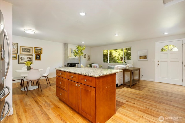 19802 33rd Dr SE, Bothell, WA 98012 - kitchen with light wood finished floors, light stone counters, a fireplace, recessed lighting, and brown cabinetry