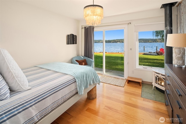 24410 Vashon Hwy SW, Vashon, WA 98070 - bedroom with a wood stove, light wood-style floors, access to outside, a chandelier, and a water view