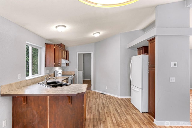 4949 Samish Way Unit 17, Bellingham, WA 98229 - kitchen featuring white appliances, a peninsula, a sink, light wood-style flooring, and light countertops