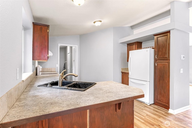 4949 Samish Way Unit 17, Bellingham, WA 98229 - kitchen featuring freestanding refrigerator, a peninsula, a sink, light wood-style floors, and light countertops