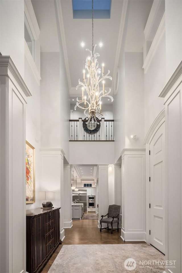 1848 77th Ave NE, Medina, WA 98039 - entryway with a towering ceiling, a decorative wall, wood finished floors, a chandelier, and ornamental molding