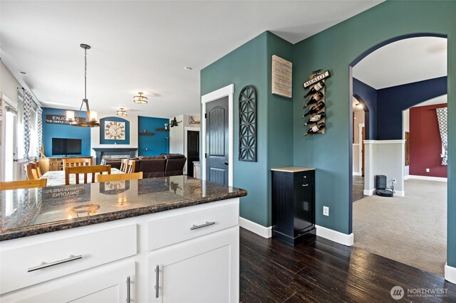 22306 137th Ave E, Graham, WA 98338 - kitchen featuring dark stone counters, white cabinetry, arched walkways, open floor plan, and dark wood-type flooring