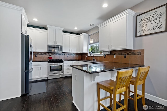 22306 137th Ave E, Graham, WA 98338 - kitchen featuring appliances with stainless steel finishes, a sink, a peninsula, dark wood-type flooring, and white cabinets