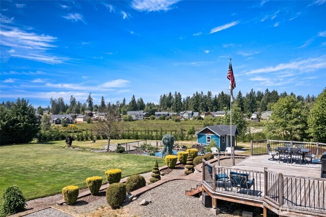 22306 137th Ave E, Graham, WA 98338 - view of grassy yard with outdoor dining area, a deck, an outbuilding, and view of wooded area