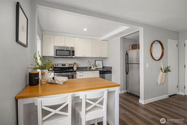 1800 Taylor Ave N Unit 1, Seattle, WA 98109 - kitchen featuring stainless steel appliances, a sink, dark wood-style flooring, a peninsula, and white cabinets