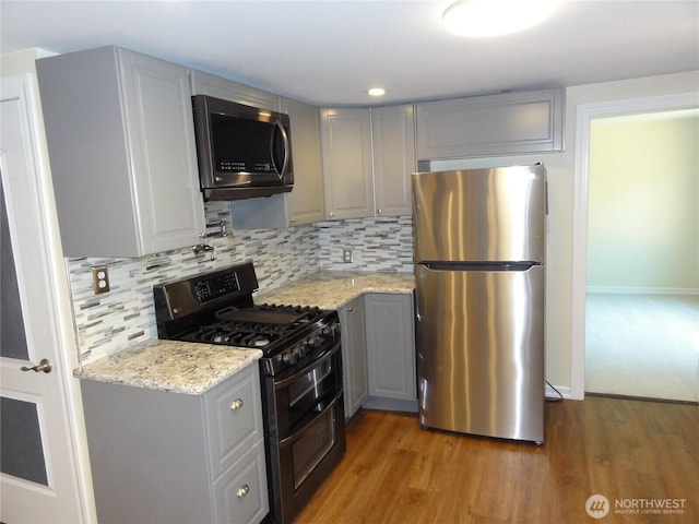 1242 Lidstrom Rd E, Port Orchard, WA 98366 - kitchen with appliances with stainless steel finishes, gray cabinets, light wood-style flooring, tasteful backsplash, and light stone countertops
