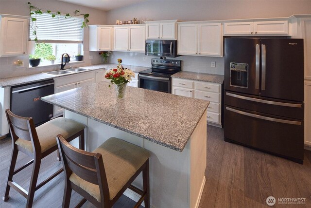 15437 104th Way SE, Yelm, WA 98597 - kitchen featuring stainless steel appliances, white cabinetry, dark wood-style floors, a kitchen breakfast bar, and decorative backsplash