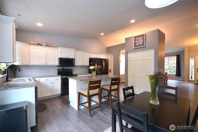 15437 104th Way SE, Yelm, WA 98597 - kitchen featuring black appliances, tasteful backsplash, dark wood-style floors, a kitchen island, and white cabinetry