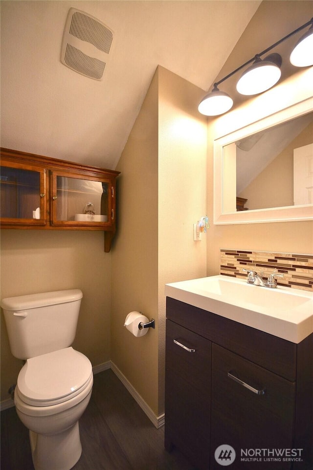 15437 104th Way SE, Yelm, WA 98597 - half bathroom with vaulted ceiling, vanity, wood finished floors, and backsplash