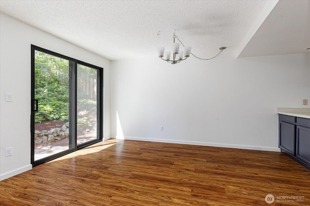 111 NW Columbia Dr Unit B7, Oak Harbor, WA 98277 - unfurnished dining area featuring a textured ceiling, a chandelier, wood finished floors, and baseboards