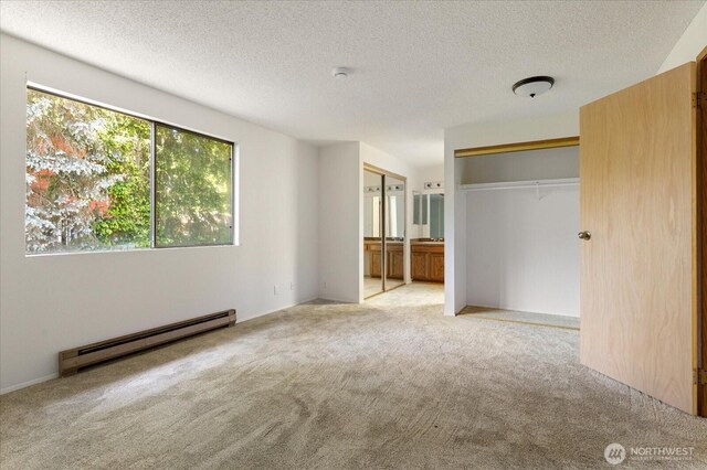111 NW Columbia Dr Unit B7, Oak Harbor, WA 98277 - unfurnished bedroom featuring baseboard heating, light colored carpet, a textured ceiling, and connected bathroom