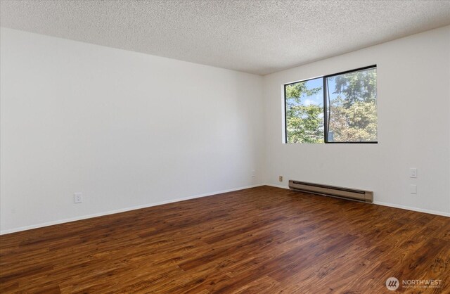 111 NW Columbia Dr Unit B7, Oak Harbor, WA 98277 - empty room with a baseboard radiator, wood finished floors, a textured ceiling, and baseboards