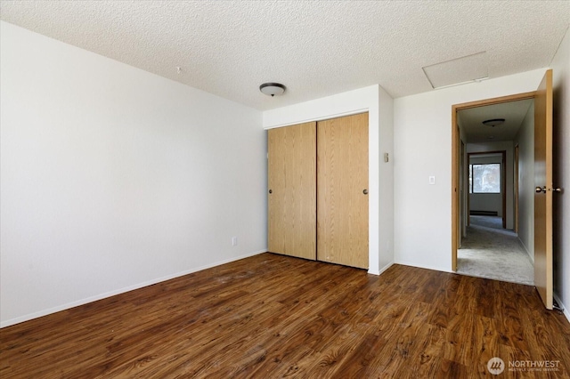 111 NW Columbia Dr Unit B7, Oak Harbor, WA 98277 - unfurnished bedroom with attic access, dark wood finished floors, a closet, a textured ceiling, and baseboards