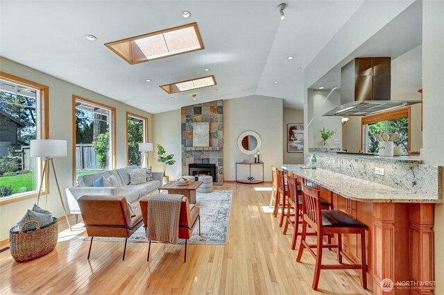 3222 107th Ave SE, Bellevue, WA 98004 - living room with a skylight, light wood-style floors, vaulted ceiling, a fireplace, and recessed lighting