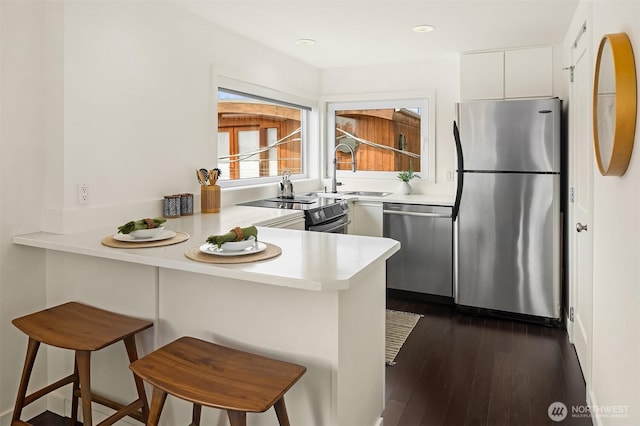 2031 Fairview Ave E Unit E, Seattle, WA 98102 - kitchen featuring appliances with stainless steel finishes, a sink, a peninsula, light countertops, and white cabinetry