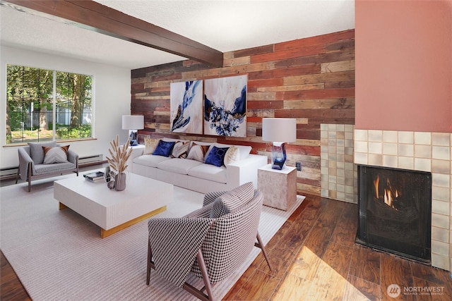 16817 21st Ave E, Spanaway, WA 98387 - living room with a tiled fireplace, wood finished floors, wood walls, beam ceiling, and a baseboard radiator