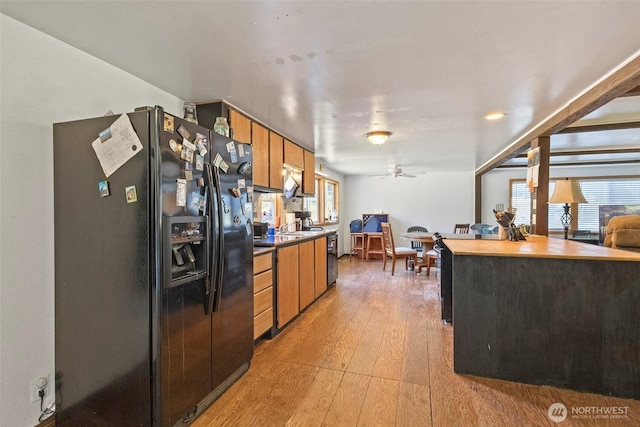 1269 Hideaway Ln, Oak Harbor, WA 98277 - kitchen with black refrigerator with ice dispenser, light wood-style flooring, brown cabinets, ceiling fan, and stainless steel dishwasher
