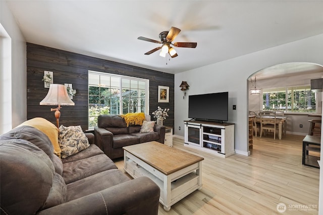 15329 Mckee Ln SE, Yelm, WA 98597 - living area with a ceiling fan, arched walkways, an accent wall, wood walls, and baseboards