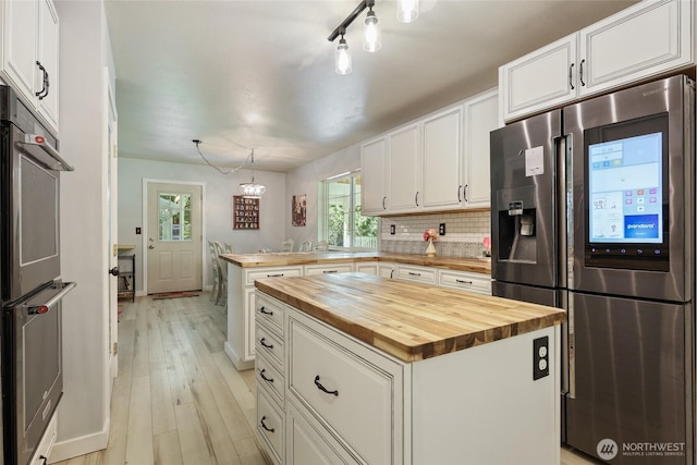 15329 Mckee Ln SE, Yelm, WA 98597 - kitchen featuring butcher block counters, appliances with stainless steel finishes, a peninsula, and white cabinetry
