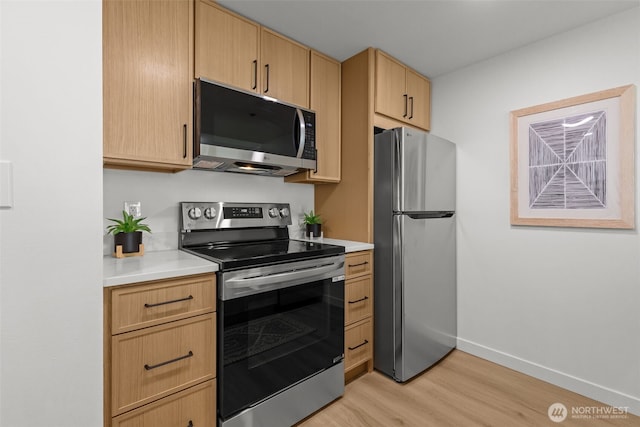 2600 2nd Ave Unit 504, Seattle, WA 98121 - kitchen with appliances with stainless steel finishes, light wood-style floors, light brown cabinets, light countertops, and baseboards