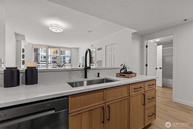 2600 2nd Ave Unit 504, Seattle, WA 98121 - kitchen featuring dishwasher, a sink, light wood-type flooring, brown cabinetry, and light stone countertops
