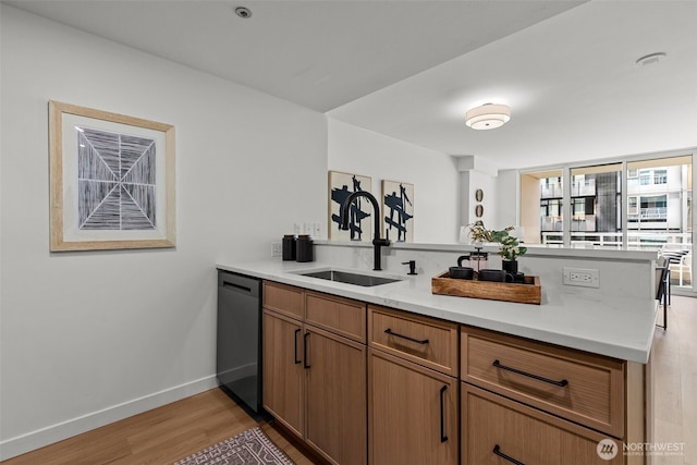2600 2nd Ave Unit 504, Seattle, WA 98121 - kitchen featuring dishwashing machine, a sink, a peninsula, light wood-style floors, and baseboards