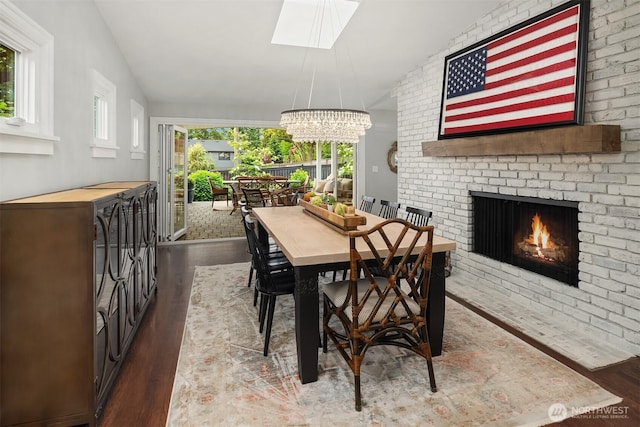 7834 SE 75th Pl, Mercer Island, WA 98040 - dining space featuring wood finished floors, a skylight, a brick fireplace, a chandelier, and vaulted ceiling