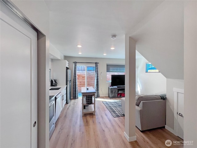 1042 S Donovan St Unit 5, Seattle, WA 98108 - kitchen with a sink, freestanding refrigerator, light wood-style floors, light countertops, and white cabinets