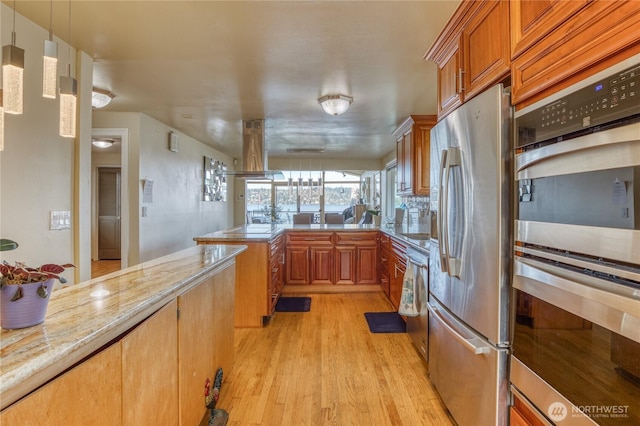 10008 Rainier Ave S, Seattle, WA 98178 - kitchen featuring a peninsula, stainless steel appliances, island range hood, light wood-style floors, and brown cabinets
