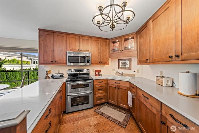2360 43rd Ave E Unit 302, Seattle, WA 98112 - kitchen with stainless steel appliances, a sink, a chandelier, and brown cabinetry