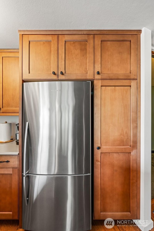 2360 43rd Ave E Unit 302, Seattle, WA 98112 - kitchen featuring freestanding refrigerator, brown cabinets, a textured ceiling, and light countertops