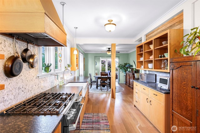2218 Williams St, Bellingham, WA 98225 - kitchen with premium range hood, stainless steel range with gas stovetop, dark countertops, light wood finished floors, and tasteful backsplash