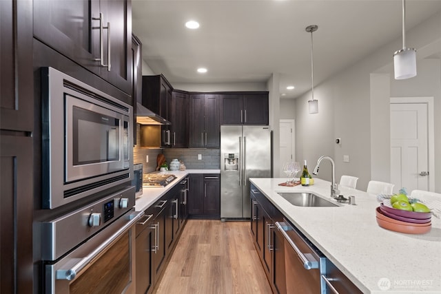 4408 214th Pl SE, Bothell, WA 98021 - kitchen featuring stainless steel appliances, a sink, light wood-style floors, light stone counters, and decorative light fixtures
