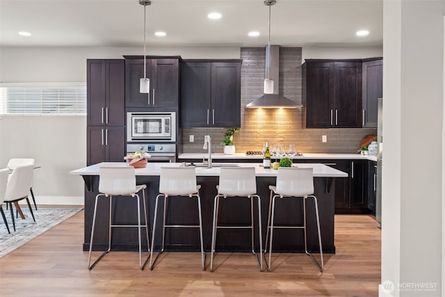 4408 214th Pl SE, Bothell, WA 98021 - kitchen featuring wall chimney exhaust hood, stainless steel appliances, a breakfast bar area, an island with sink, and recessed lighting
