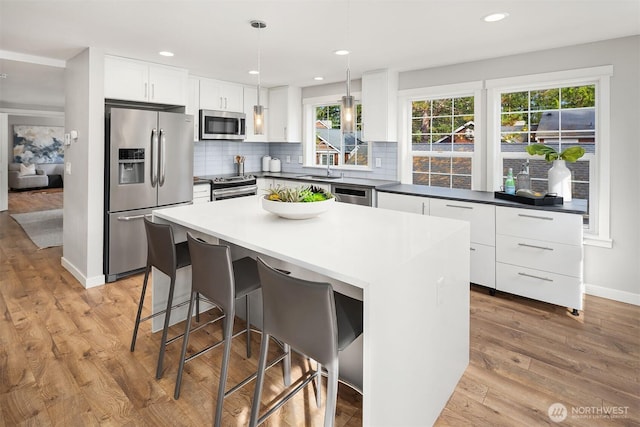 3046 128th Ave SE Unit 30, Bellevue, WA 98005 - kitchen featuring appliances with stainless steel finishes, white cabinets, light wood-style flooring, decorative backsplash, and recessed lighting